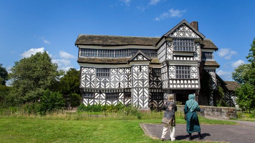 Two visitors walk towards the front of Little Moreton Hall, Cheshire